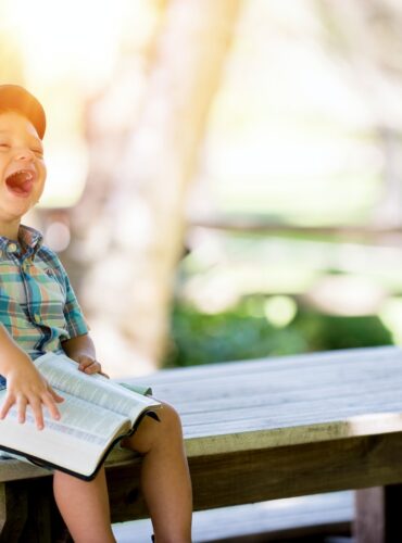 boy sitting on bench while holding a book