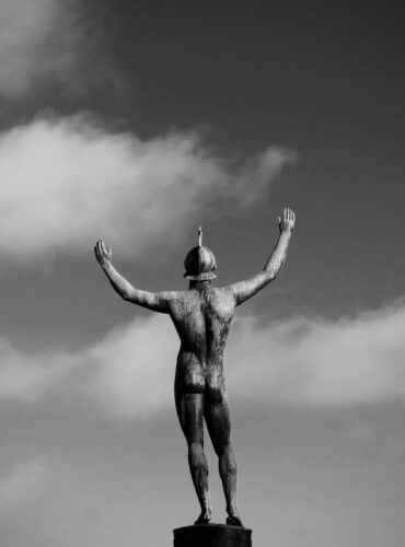 grayscale photo of man raising his right hand statue