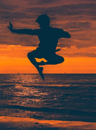 silhouette of man jump on seashore