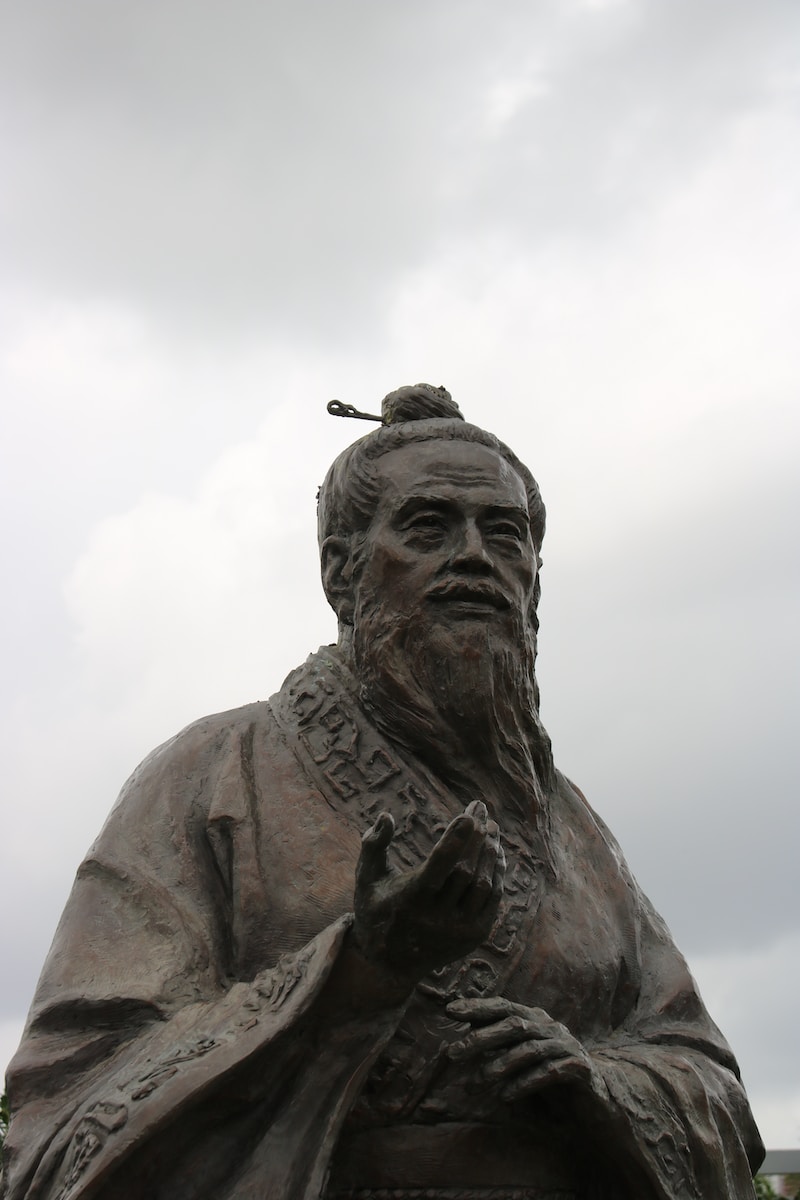 man in hat statue under white clouds during daytime