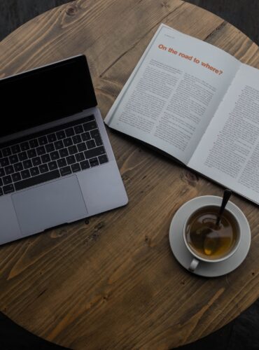 gray laptop beside white teacup and book