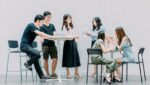 two men and four women meeting in office